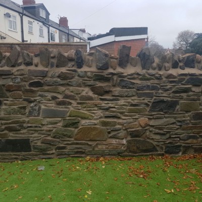 Random stone walling with brick work. Rebuilt using original stone.